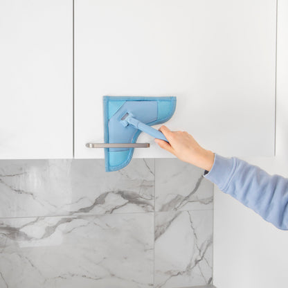Person cleaning a marble countertop with a blue cleaning tool.