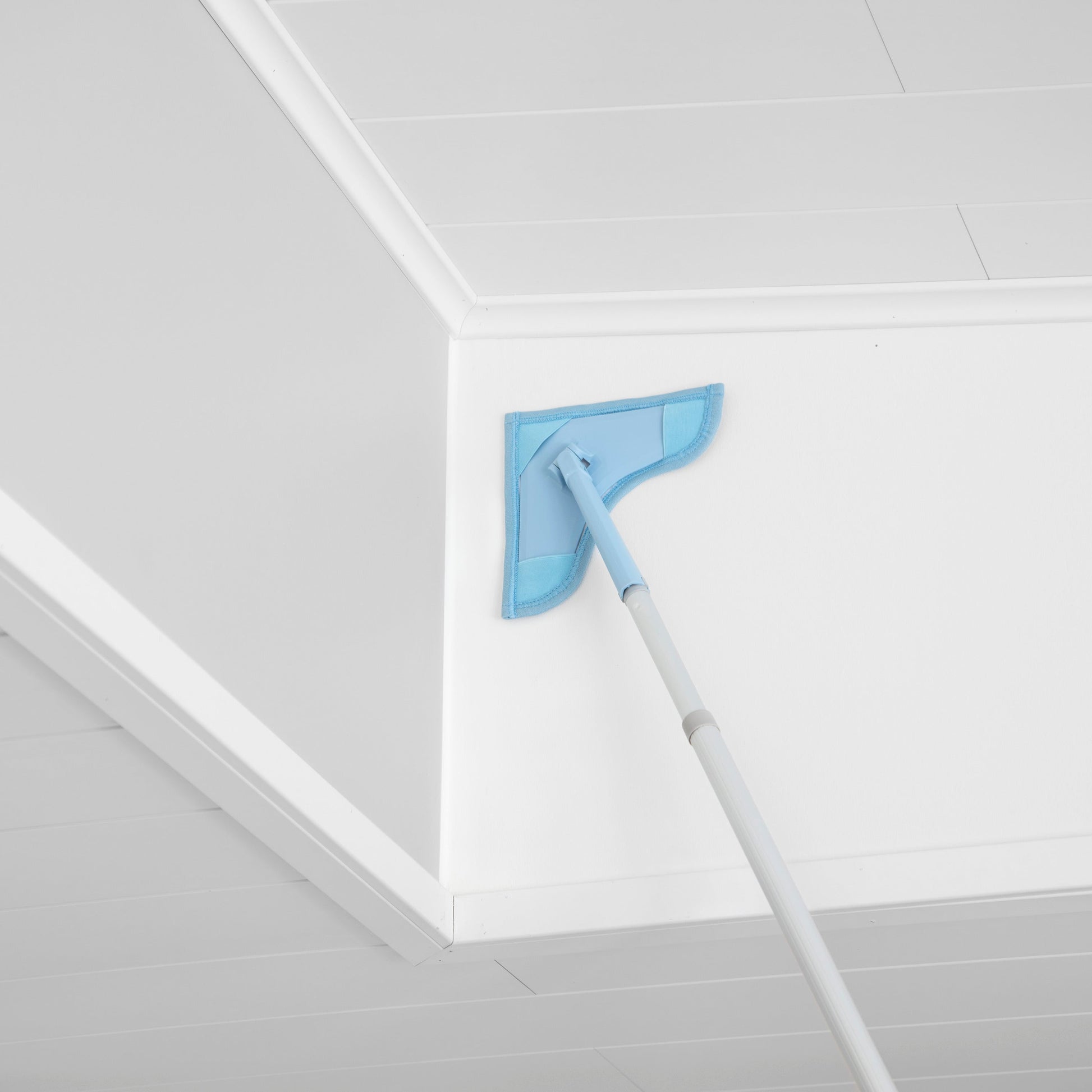 Cleaning tool with blue pad on a white ceiling